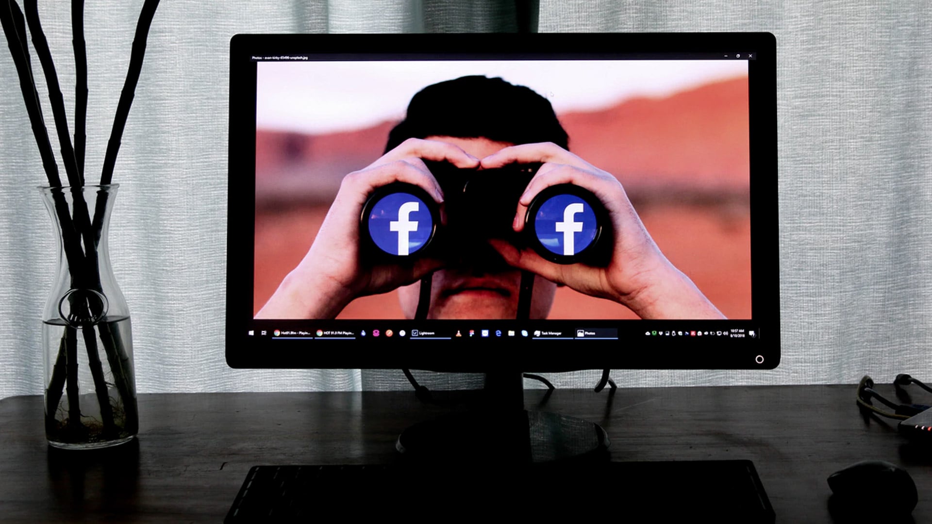 Op een computermonitor wordt een beeld weergegeven van een persoon die door een verrekijker kijkt, met het Facebook-logo op elke lens. De monitor staat op een donker bureau met aan de rechterkant een bril en aan de linkerkant een glazen vaas met zwarte stokken en vraagt: "Hoe bereik jij de juiste generatie op sociale media?